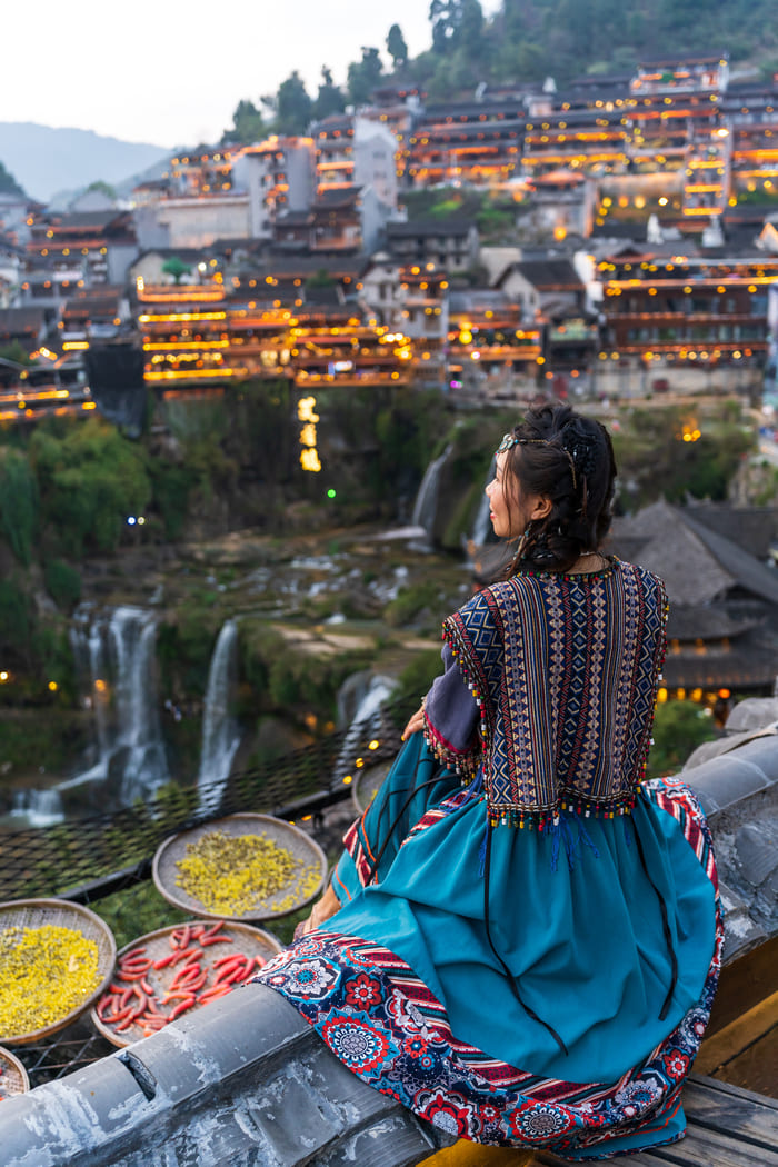 Niña China sentada observando cual hermosa es la gran ciudad